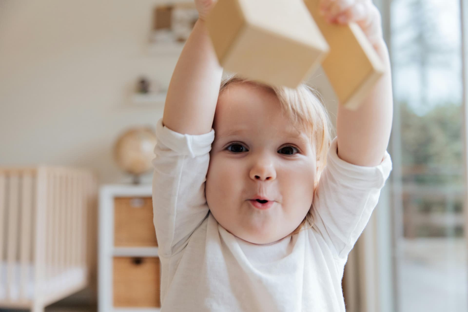 Famille réunie autour d'un bébé qui sourit, entourée de décorations colorées pour une fête prénatale.